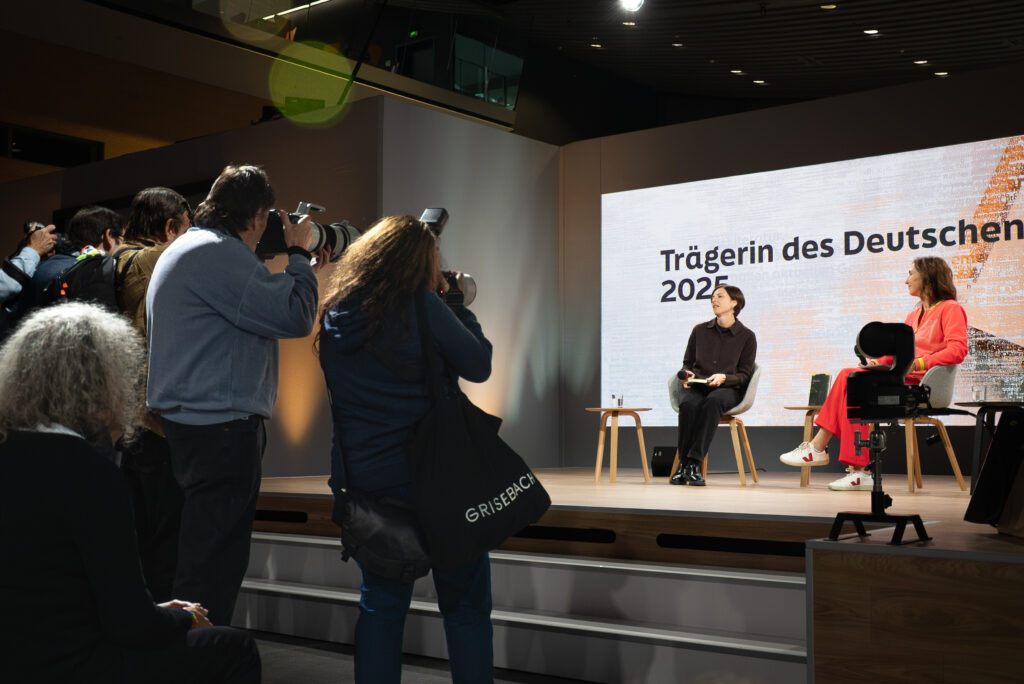 Dorothee Elmiger sitzt auf der Literaturbühne, vor ihr stehen mehrere Pressefotograf*innen