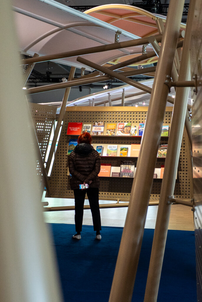 Messebesucherin schaut sich Bücher an.