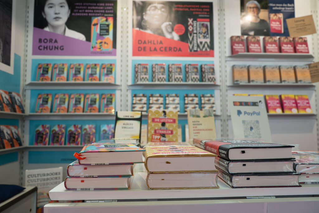 Büchertisch im Vordergrund, im Hintergrund die Ausstellungswände und Plakate.