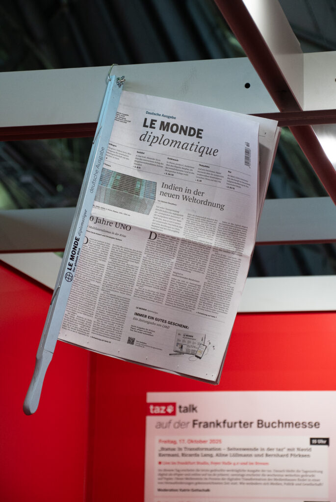 Eine Ausgabe der Zeitung "LE MONDE diplomatique" hängt am Ausstellungsstand der taz.