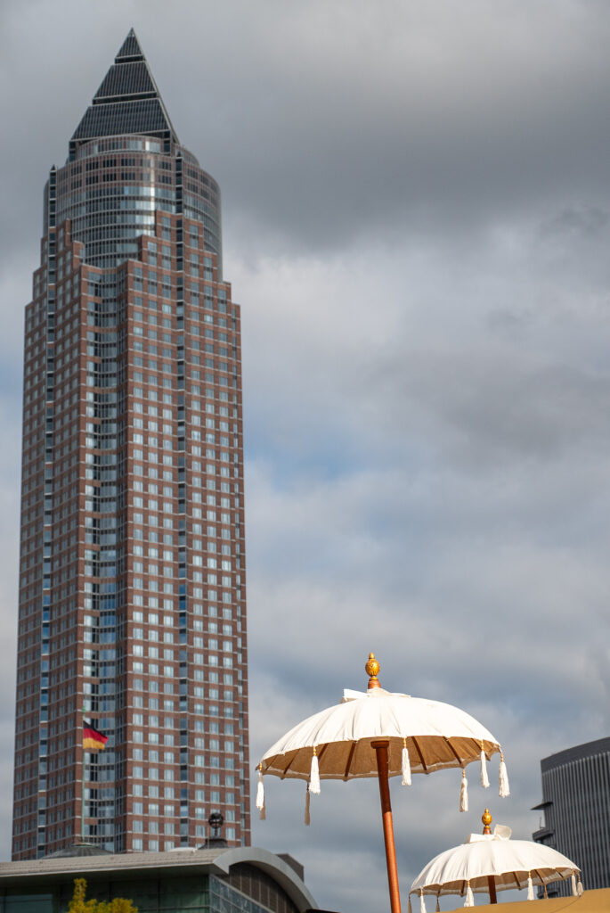 Der riesige Messeturm, im Vordergrund Dekoschirmchen von einem Essensstand.