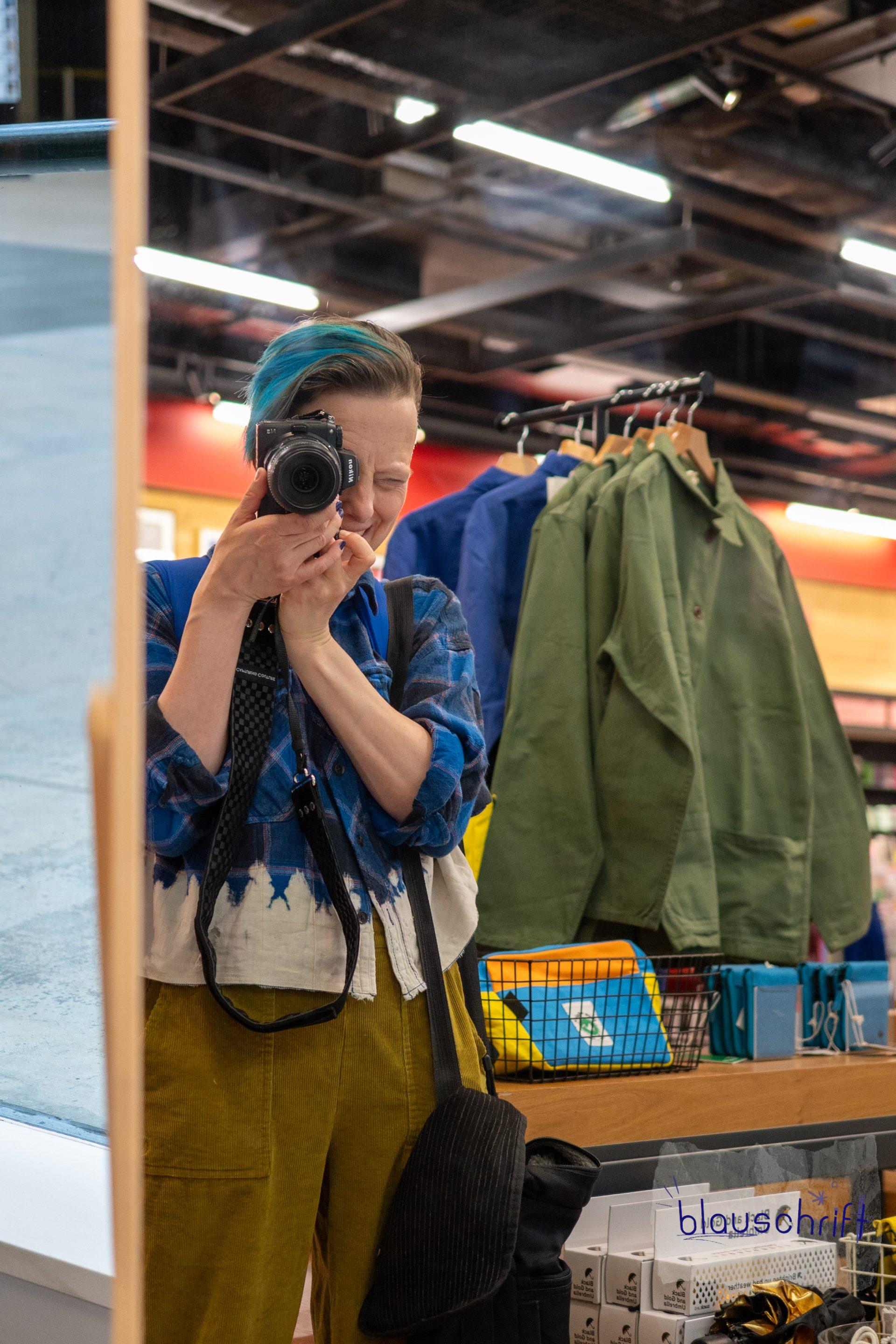 Alex fotografiert sich in einem Museumsshop in einem Spiegel.
