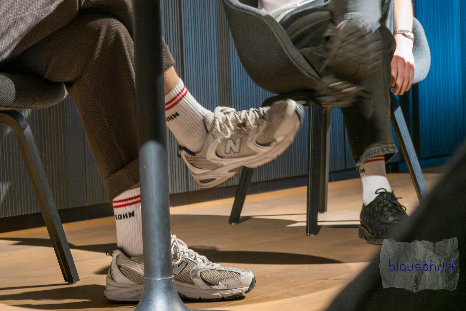 Autor und Modertor zeigen unter dem Tisch ihre Merchandise-Socken, auf denen "Hundesohn" steht.